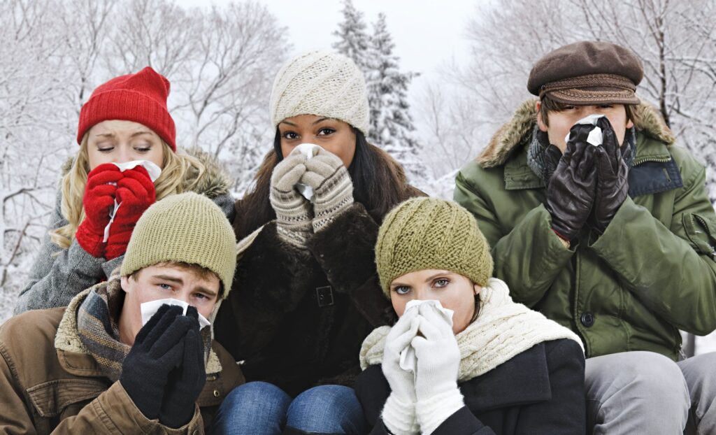 Group of young friends blowing noses outdoors in winter
