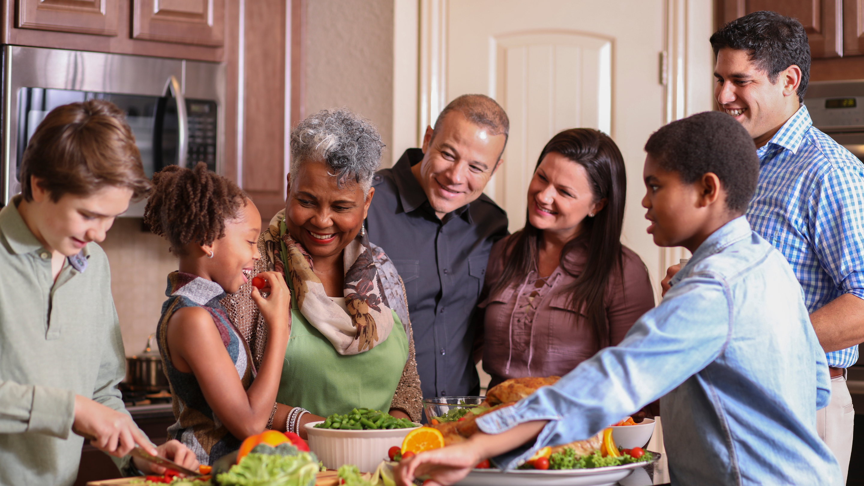 Happy people standing around table with food.