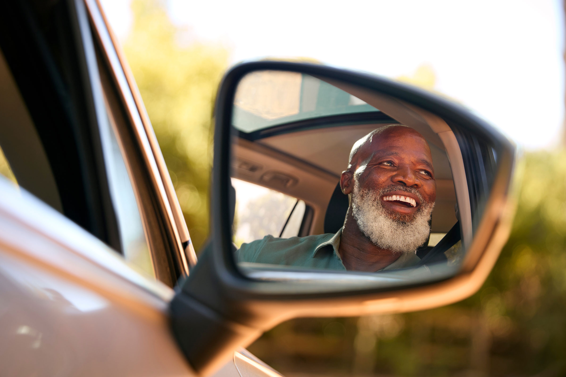 Smiling man reflected in car mirror
