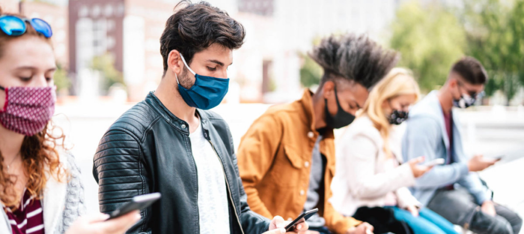 Group of people sitting on phones wearing masks
