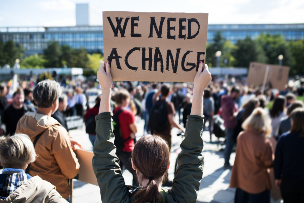 Woman holding sign stating "We need a change"