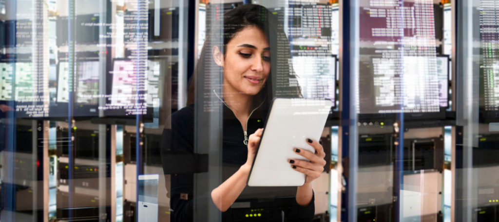 woman writing down data in server room