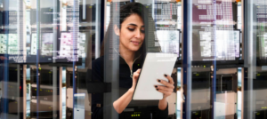 woman writing down data in server room
