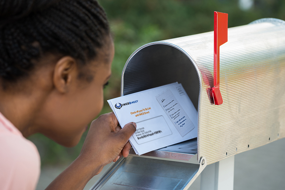 woman putting IWCO mail into mailbox